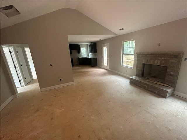 unfurnished living room featuring a brick fireplace and vaulted ceiling