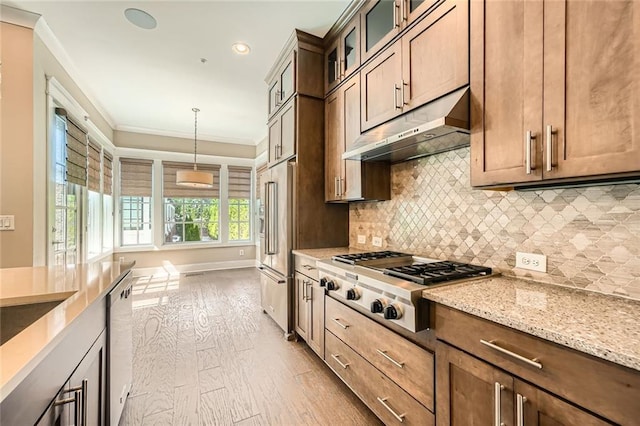 504 E Howard Ave, Decatur, GA 30030 - kitchen with under cabinet range hood, stainless steel appliances, light stone countertops, light wood-style floors, and crown molding