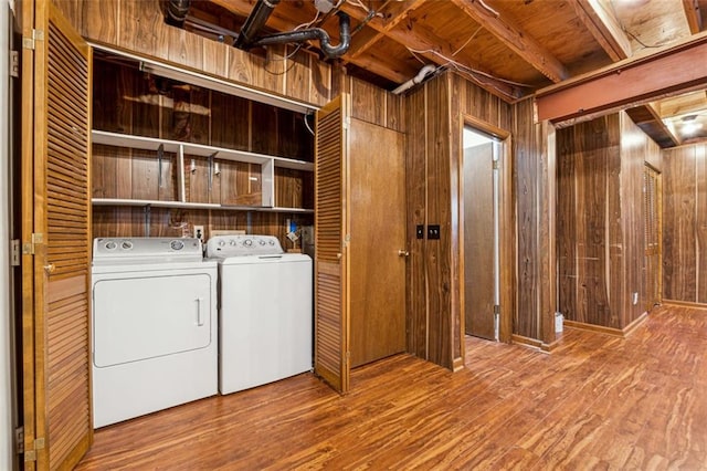 washroom with hardwood / wood-style floors, washing machine and clothes dryer, and wood walls