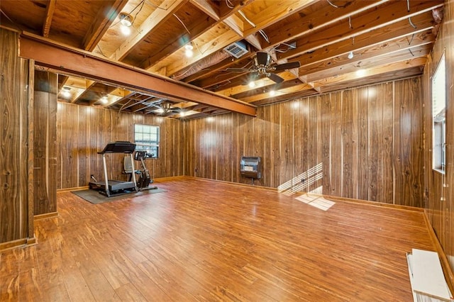 workout room with ceiling fan, hardwood / wood-style floors, and wooden walls