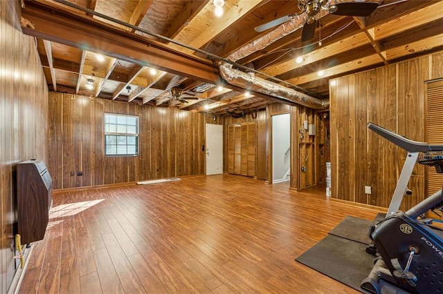 exercise area featuring hardwood / wood-style floors, ceiling fan, heating unit, and wooden walls