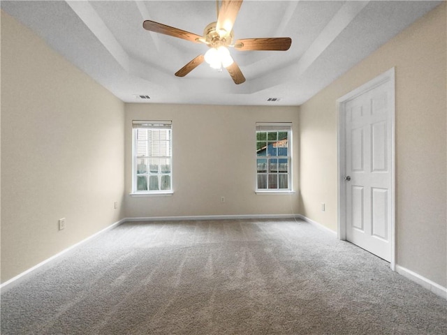 carpeted empty room with a tray ceiling and ceiling fan