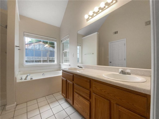 bathroom featuring tile patterned floors, a washtub, vanity, and vaulted ceiling