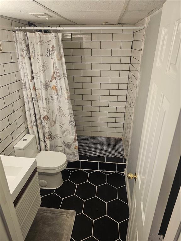 bathroom featuring a paneled ceiling, toilet, vanity, and a shower with shower curtain