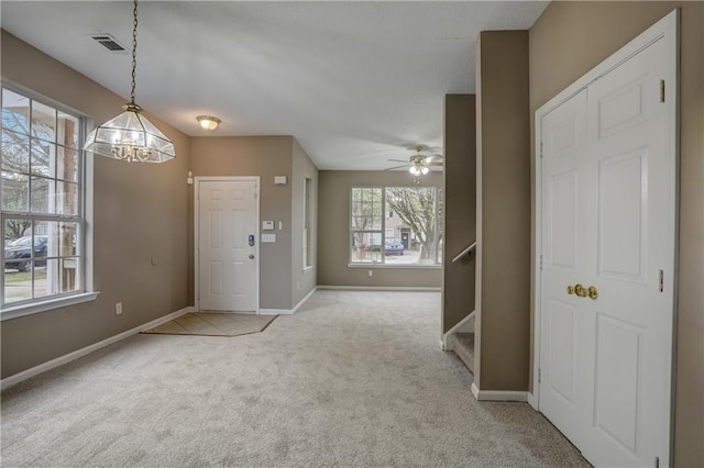 carpeted entrance foyer with ceiling fan with notable chandelier