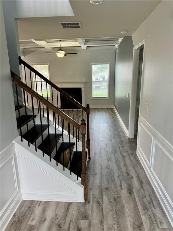 4416 Birch Meadow Trl, Gainesville, GA 30504 - stairs with wood finished floors, ceiling fan, a wainscoted wall, a decorative wall, and coffered ceiling