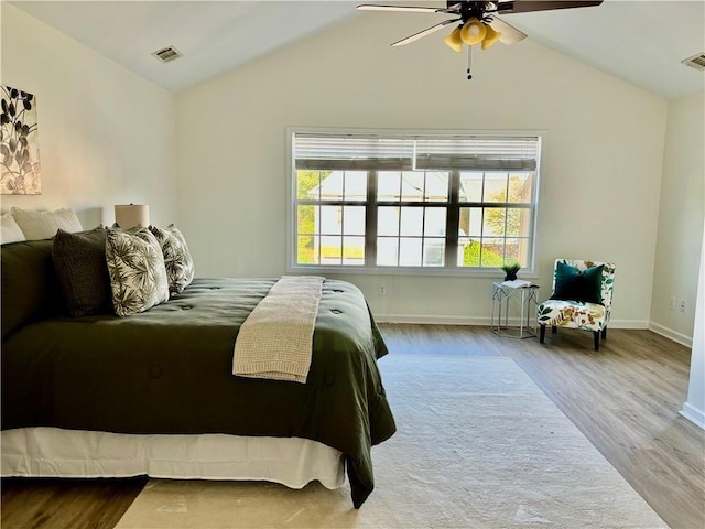 bedroom with lofted ceiling, multiple windows, visible vents, and wood finished floors