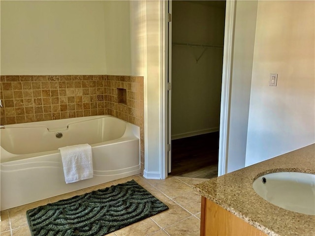 full bathroom featuring a spacious closet, vanity, a bath, and tile patterned floors