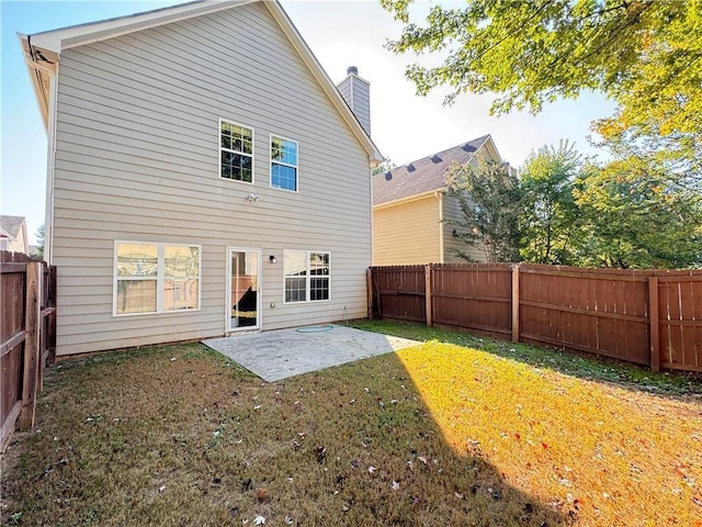 back of house featuring a chimney, a patio area, a lawn, and a fenced backyard