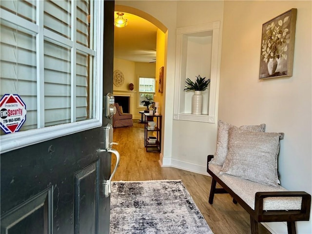 interior space featuring arched walkways, wood finished floors, and baseboards