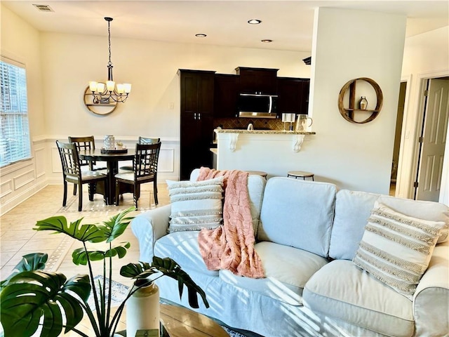 living area featuring a chandelier, recessed lighting, a wainscoted wall, a decorative wall, and visible vents