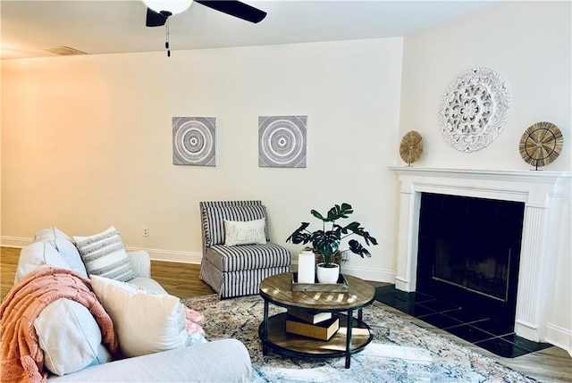 living area featuring a fireplace, wood finished floors, visible vents, a ceiling fan, and baseboards