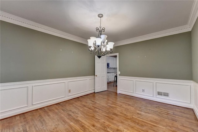 unfurnished room featuring light hardwood / wood-style floors, a chandelier, and ornamental molding