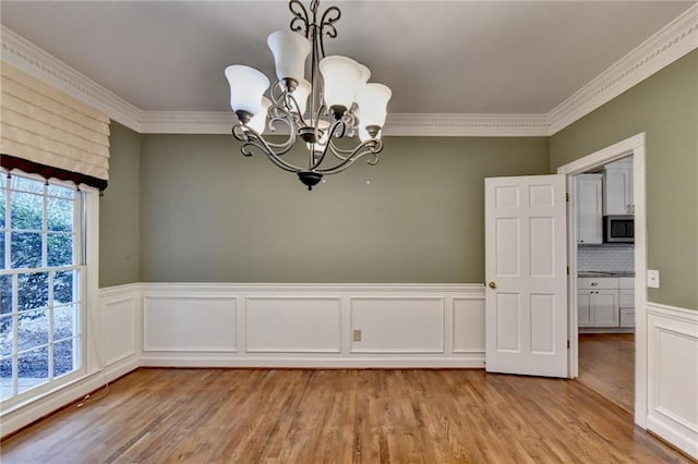 unfurnished dining area featuring ornamental molding, a chandelier, and light hardwood / wood-style floors