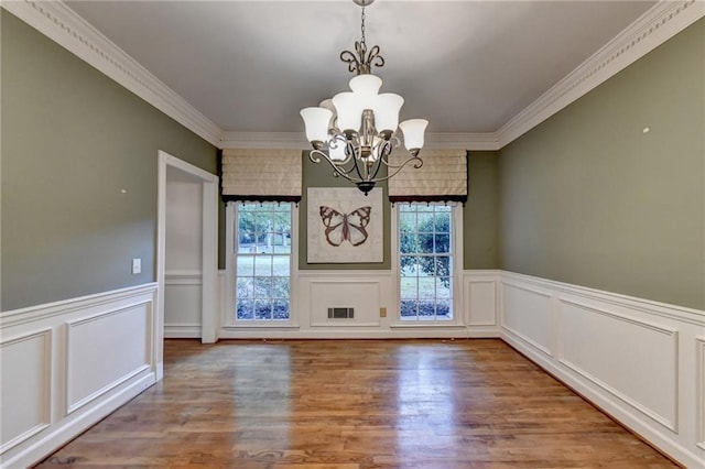 unfurnished dining area featuring crown molding, hardwood / wood-style floors, and a chandelier