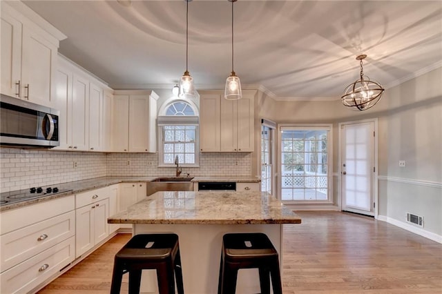 kitchen with sink, light hardwood / wood-style flooring, a center island, a breakfast bar, and cooktop