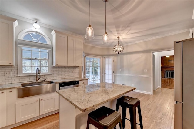 kitchen with a center island, stainless steel appliances, light hardwood / wood-style floors, white cabinetry, and a breakfast bar area