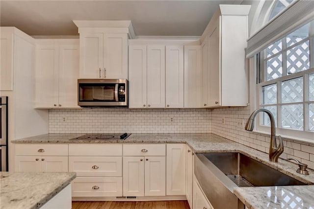 kitchen with light stone counters, a wealth of natural light, sink, and backsplash