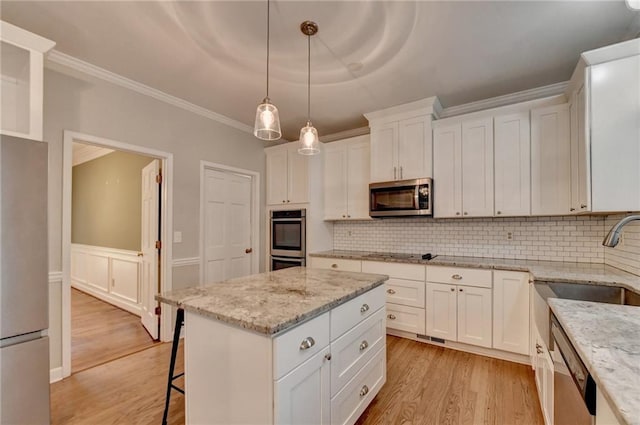 kitchen featuring light wood-type flooring, light stone countertops, decorative backsplash, white cabinets, and appliances with stainless steel finishes