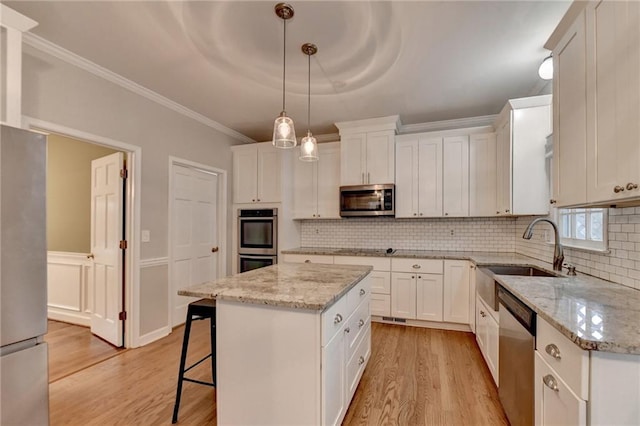 kitchen featuring pendant lighting, light hardwood / wood-style flooring, white cabinets, appliances with stainless steel finishes, and a center island