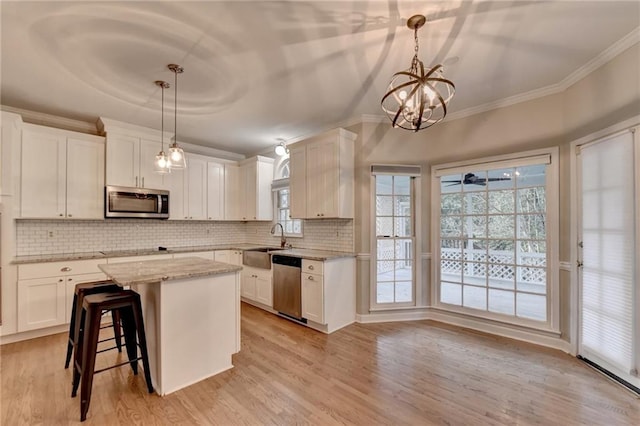 kitchen featuring appliances with stainless steel finishes, decorative light fixtures, and white cabinets