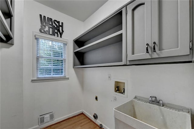 laundry room with wood-type flooring, hookup for an electric dryer, sink, washer hookup, and cabinets