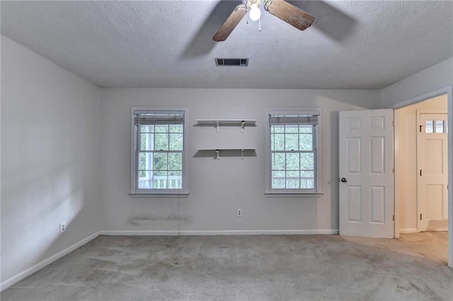 carpeted spare room featuring plenty of natural light, ceiling fan, and a textured ceiling