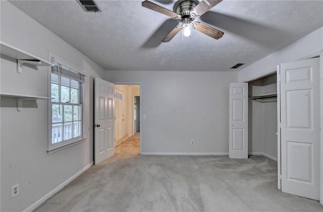 unfurnished bedroom featuring ceiling fan, a textured ceiling, a closet, and light carpet