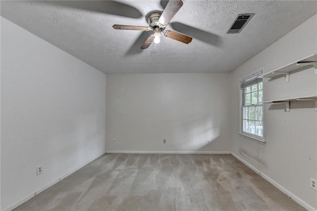 empty room featuring light carpet, ceiling fan, and a textured ceiling