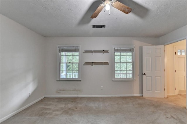 carpeted spare room featuring ceiling fan and a textured ceiling