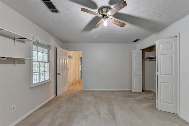 unfurnished bedroom with a closet, light colored carpet, a textured ceiling, and ceiling fan