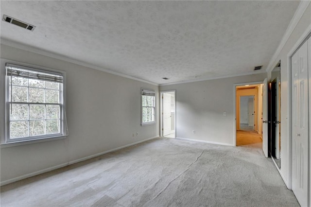 carpeted spare room with a textured ceiling, crown molding, and a healthy amount of sunlight