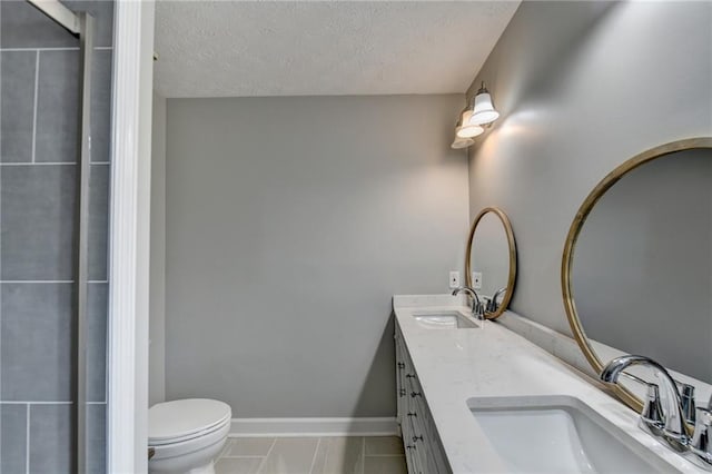 bathroom with a textured ceiling, vanity, and toilet