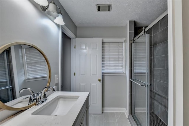 bathroom with a shower with shower door, vanity, and a textured ceiling