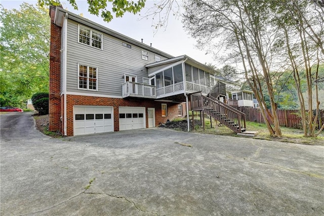 rear view of house featuring a garage and a sunroom