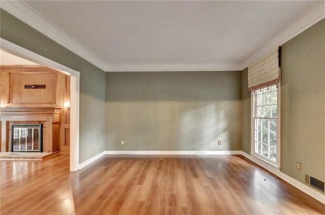 unfurnished room featuring a fireplace, ornamental molding, and hardwood / wood-style flooring