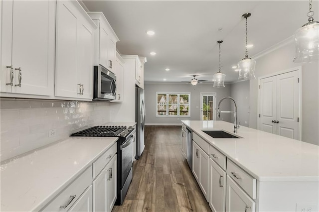 kitchen with appliances with stainless steel finishes, hanging light fixtures, an island with sink, ceiling fan, and sink