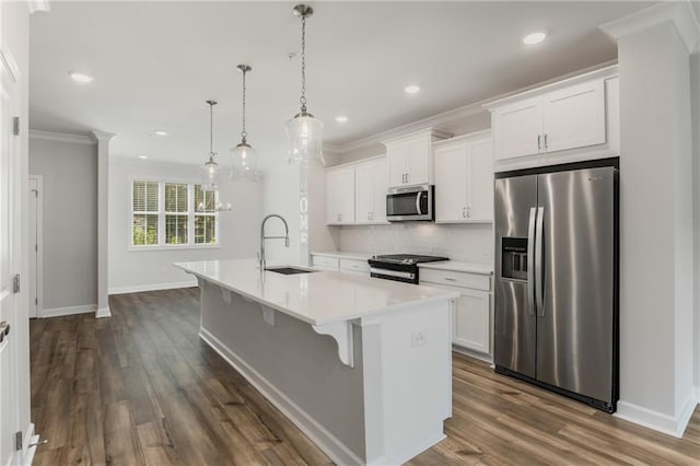 kitchen with white cabinets, a kitchen island with sink, hanging light fixtures, and appliances with stainless steel finishes