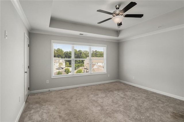 spare room featuring light carpet, a tray ceiling, and crown molding