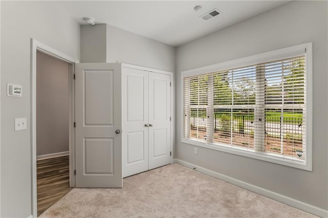 unfurnished bedroom featuring light colored carpet and a closet