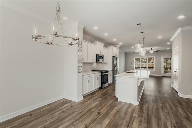 kitchen featuring decorative light fixtures, appliances with stainless steel finishes, a kitchen island with sink, and white cabinetry