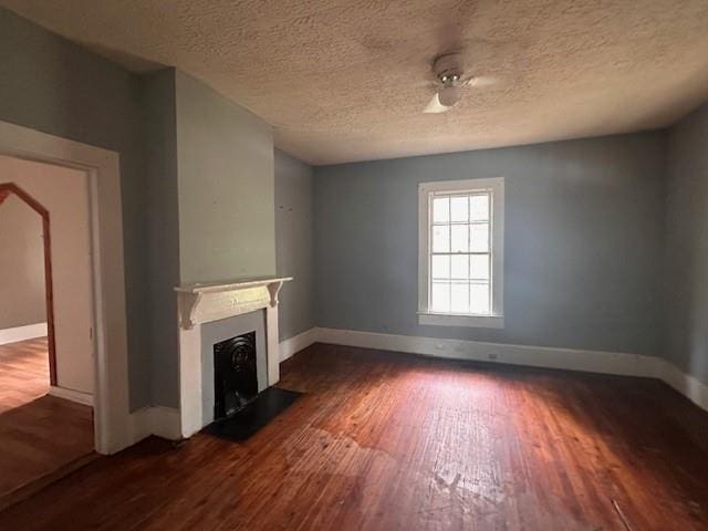 29 Ivy St, Porterdale, GA 30014 - unfurnished living room featuring dark wood finished floors, a fireplace with flush hearth, baseboards, and a textured ceiling