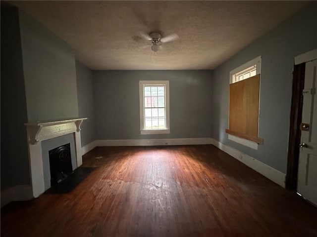 29 Ivy St, Porterdale, GA 30014 - unfurnished living room with dark wood finished floors, a fireplace with flush hearth, baseboards, a textured ceiling, and ceiling fan