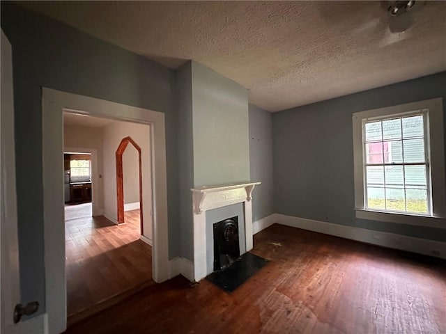 29 Ivy St, Porterdale, GA 30014 - unfurnished living room with wood finished floors, baseboards, a fireplace with flush hearth, and a textured ceiling