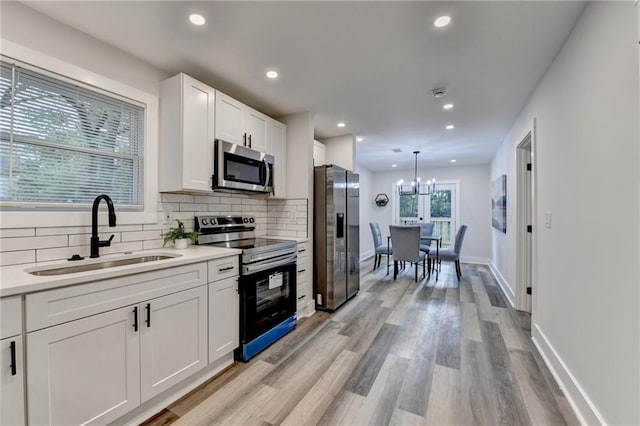 538 Center Hill Ave NW, Atlanta, GA 30318 - kitchen with tasteful backsplash, white cabinets, appliances with stainless steel finishes, a sink, and a notable chandelier