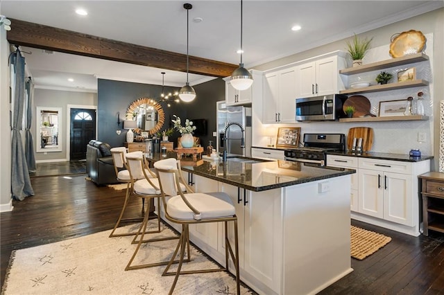 kitchen featuring a breakfast bar, sink, white cabinetry, appliances with stainless steel finishes, and an island with sink