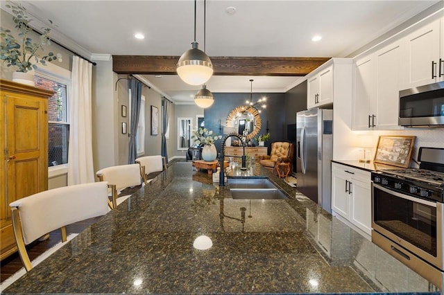 kitchen featuring sink, appliances with stainless steel finishes, dark stone countertops, hanging light fixtures, and white cabinets