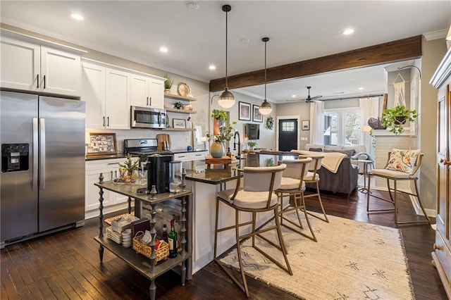 kitchen with white cabinetry, dark stone countertops, a kitchen island, pendant lighting, and stainless steel appliances