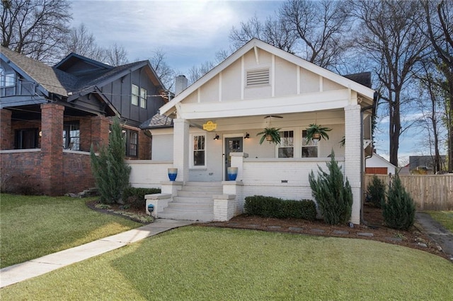 view of front of home with covered porch, ceiling fan, and a front lawn