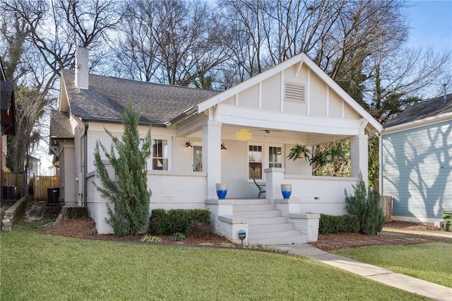 view of front facade featuring a front lawn, central air condition unit, and covered porch